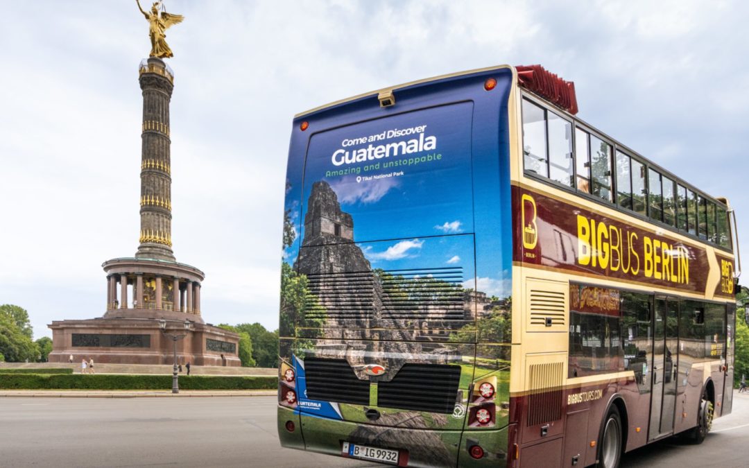 Sightseeing Bus mit Außenwerbung auf dem Busrücken fährt direkt an der Siegessäule in Berlin vorbei