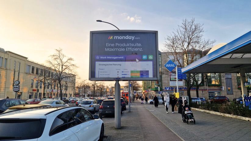 Referenzen city lights Berlin Reinickendorf. A city light board on the street Kurt-Schumacher Platz. The billboard show the company Monday.com.