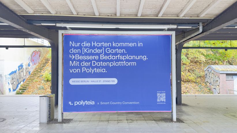 Eine analoge Großfläche am S-Bahnhof Westkreuz in Berlin. Die Plakatwerbung zeigt ein blaues Werbemotiv von der Firma Polyteia.