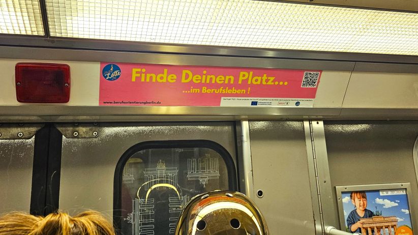 wtm Innenwerbung U-Bahn Berlin - Flotte Lotte. Im Vordergrund ist ein Seitenstreifen mit dem Motiv von Flotte Lotte, in der Berliner U-Bahn, zu sehen.